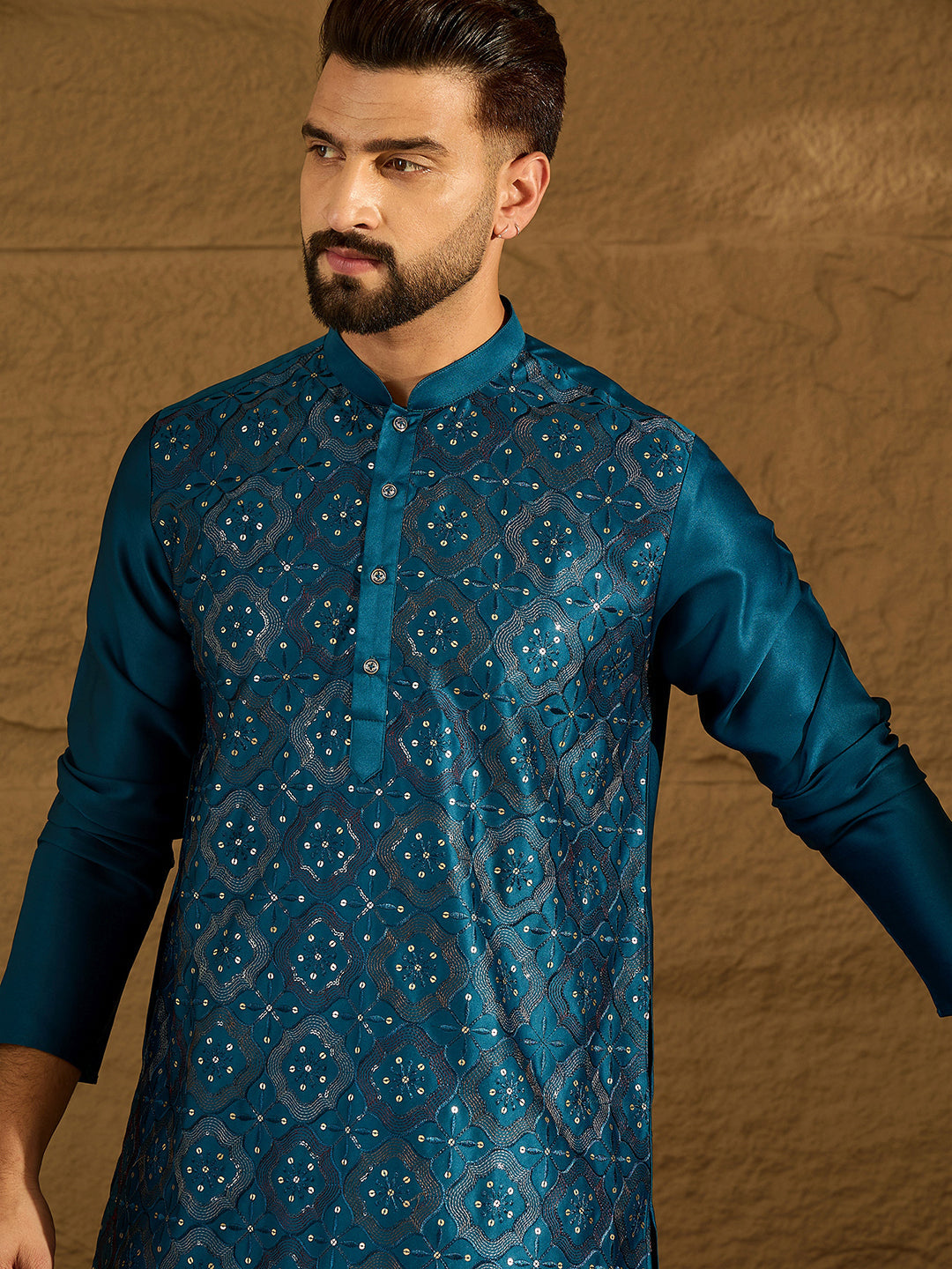 Man wearing a blue patterned kurta against a brown background